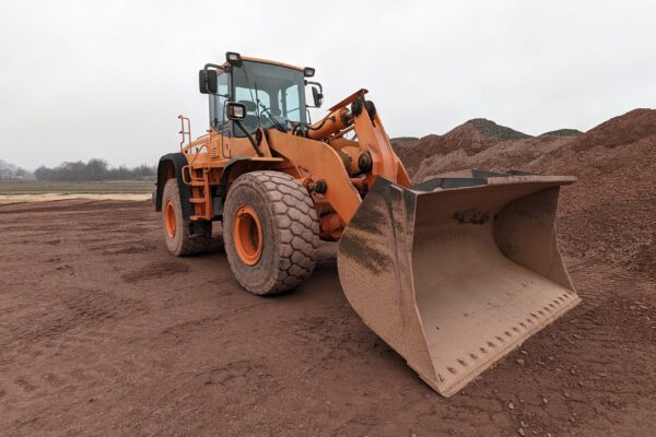 Front-end wheel loader with a large bucket at a bulk material storage yard.